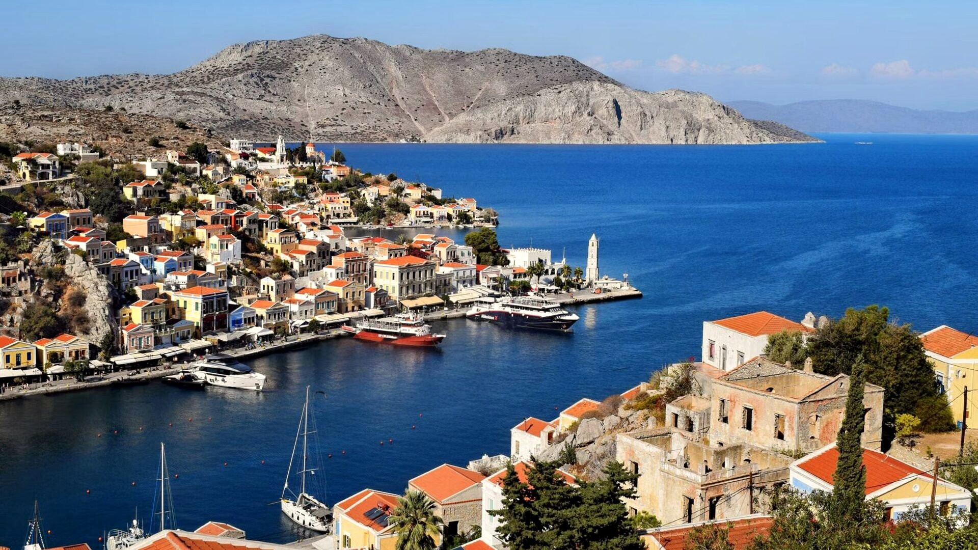 Port de Gialos et ses maisons ocre en amphithéâtre - Symi, Grèce